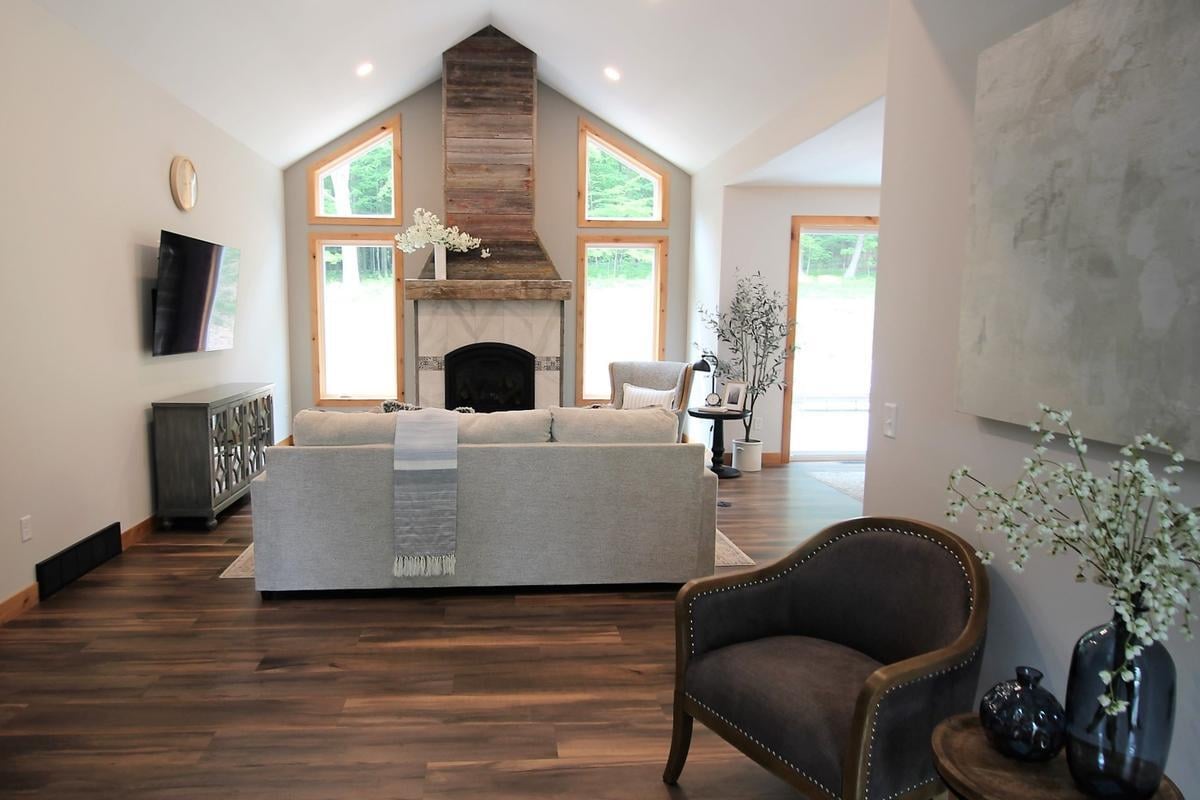 Vaulted ceiling living room with wood fireplace and large windows by Ross Construction in Lake Dubay, WI.