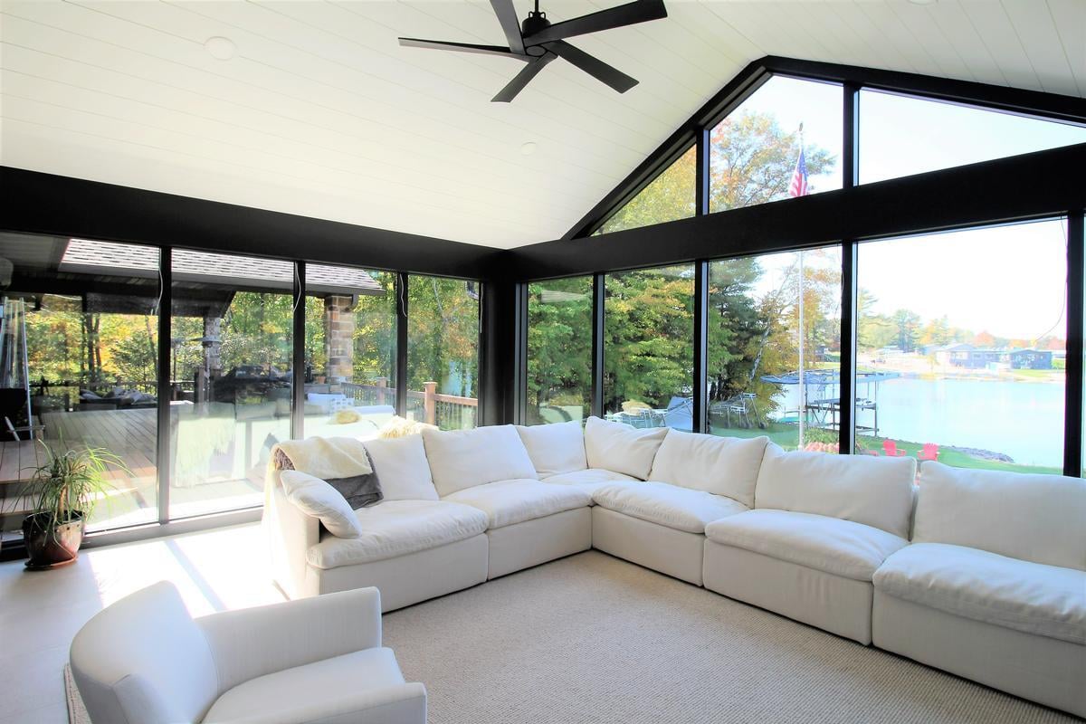 Bright lakeview sunroom with white sectional in a custom Lake Dubay, WI home by Ross Construction.