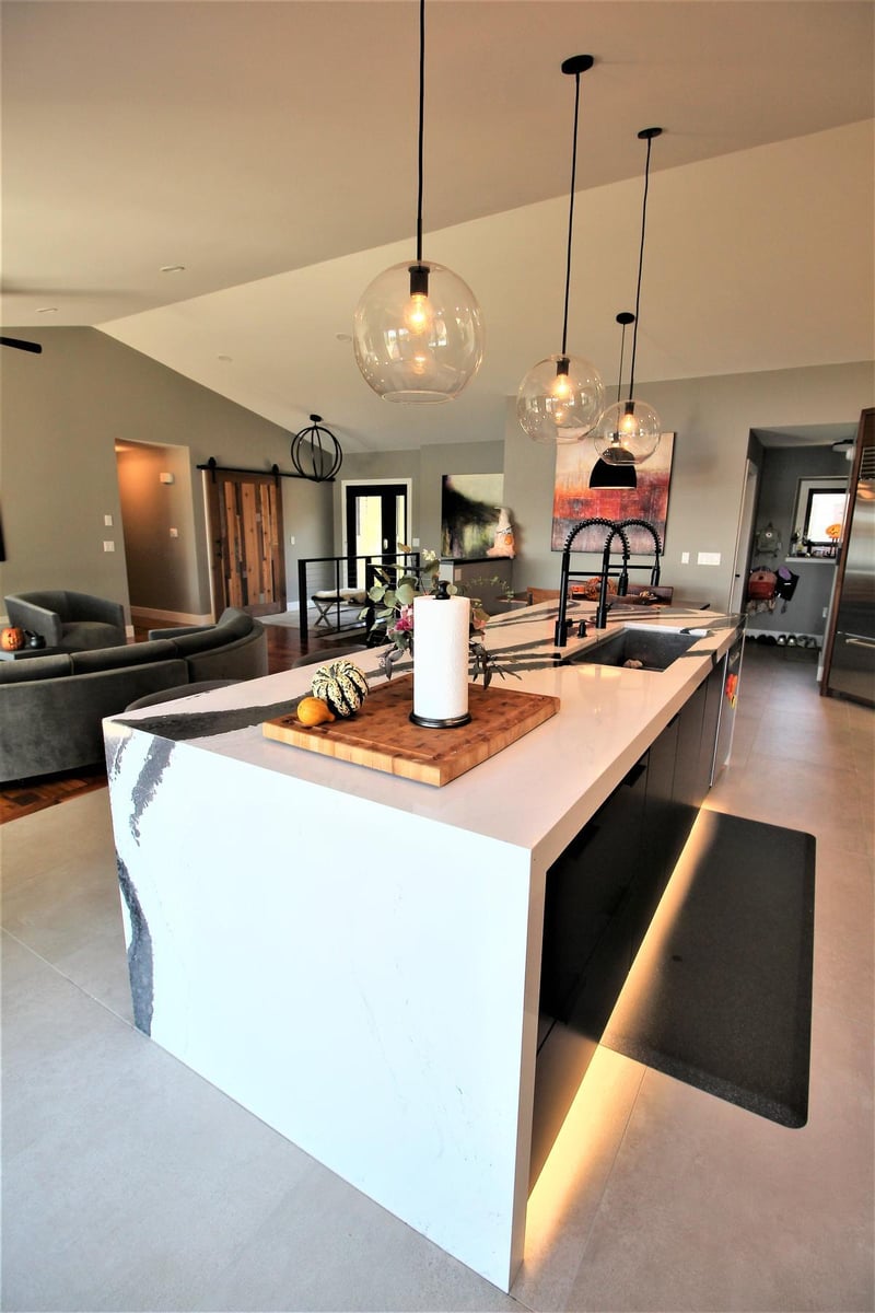 Minimalist kitchen island with waterfall quartz countertop in a custom home by Ross Construction in Rib Mountain, WI.