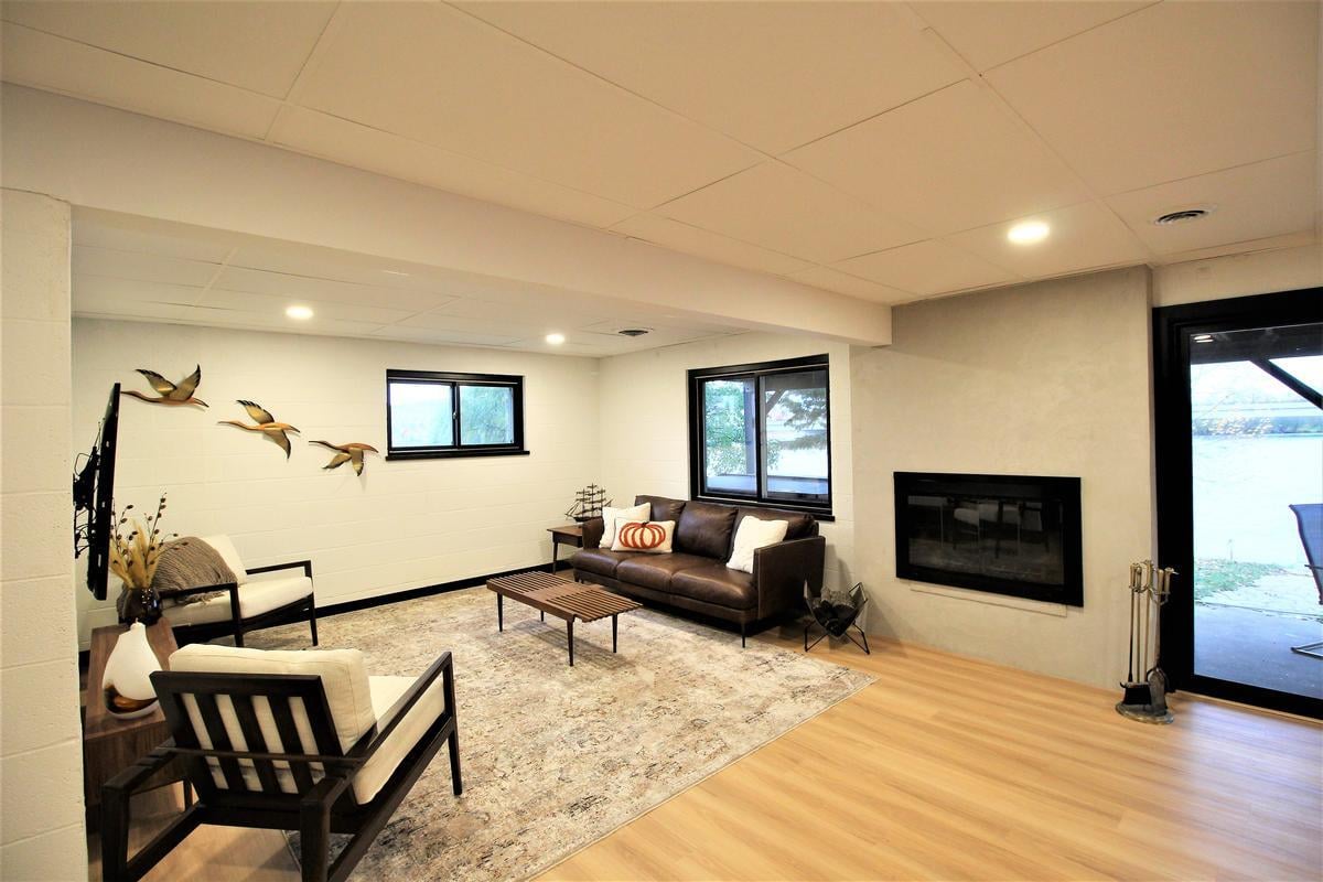 Lakeside lower-level lounge with modern fireplace in a Lake Dubay custom home by Ross Construction.