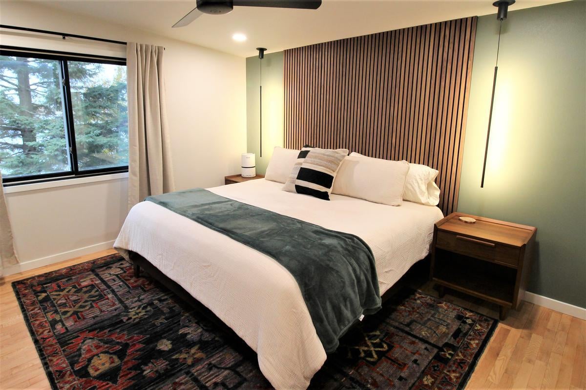 Master bedroom with wood accent wall and modern lighting in an Edgar custom home by Ross Construction.