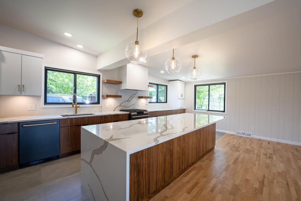 Spacious kitchen remodel in Rib Mountain custom home by Ross Construction with waterfall island and globe pendants.