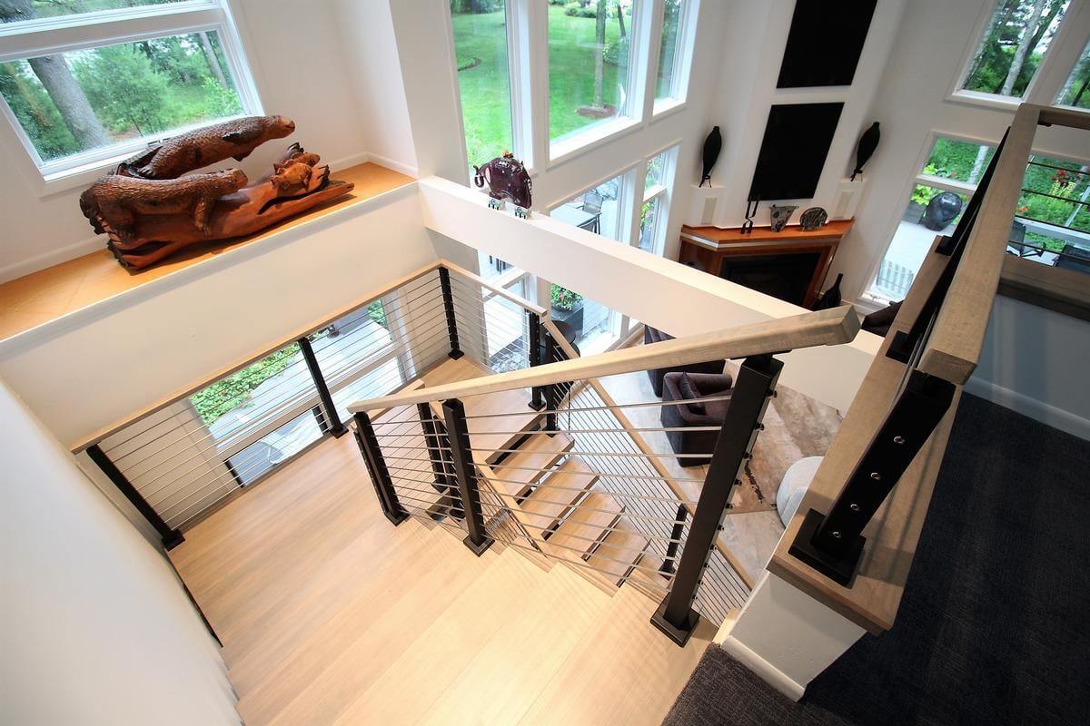 Contemporary staircase and second-floor view of bright great room in Lake Dubay home by Ross Construction.
