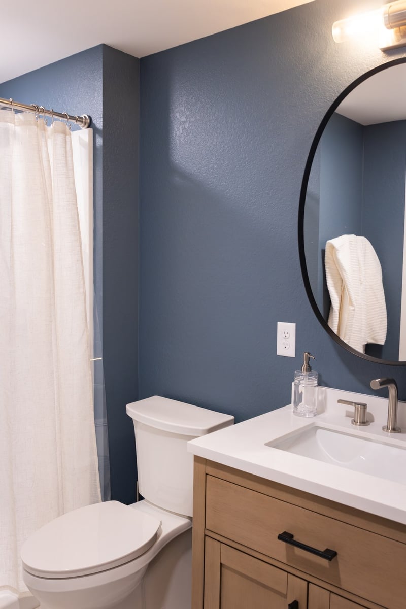 whole home remodel bathroom with slate blue walls and round black mirror minocqua wi