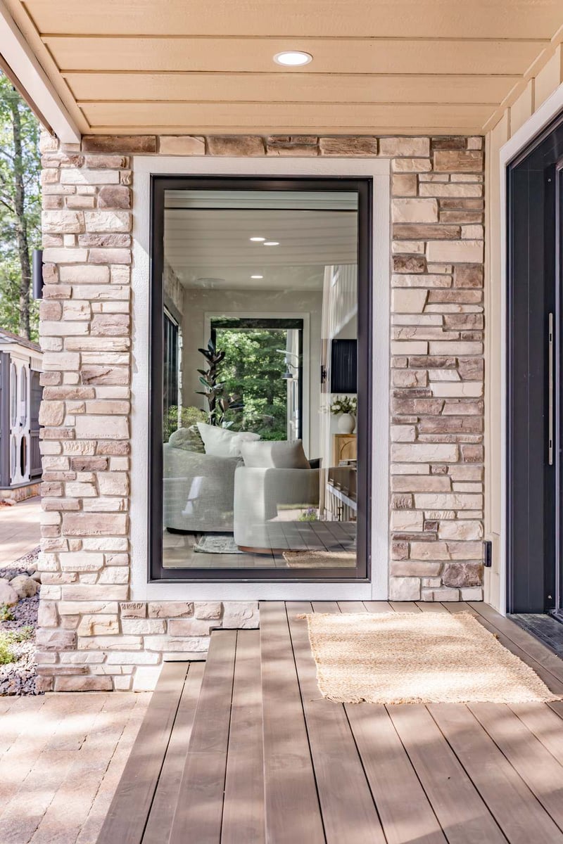 whole home remodel exterior covered porch with stone columns and sliding door minocqua wi