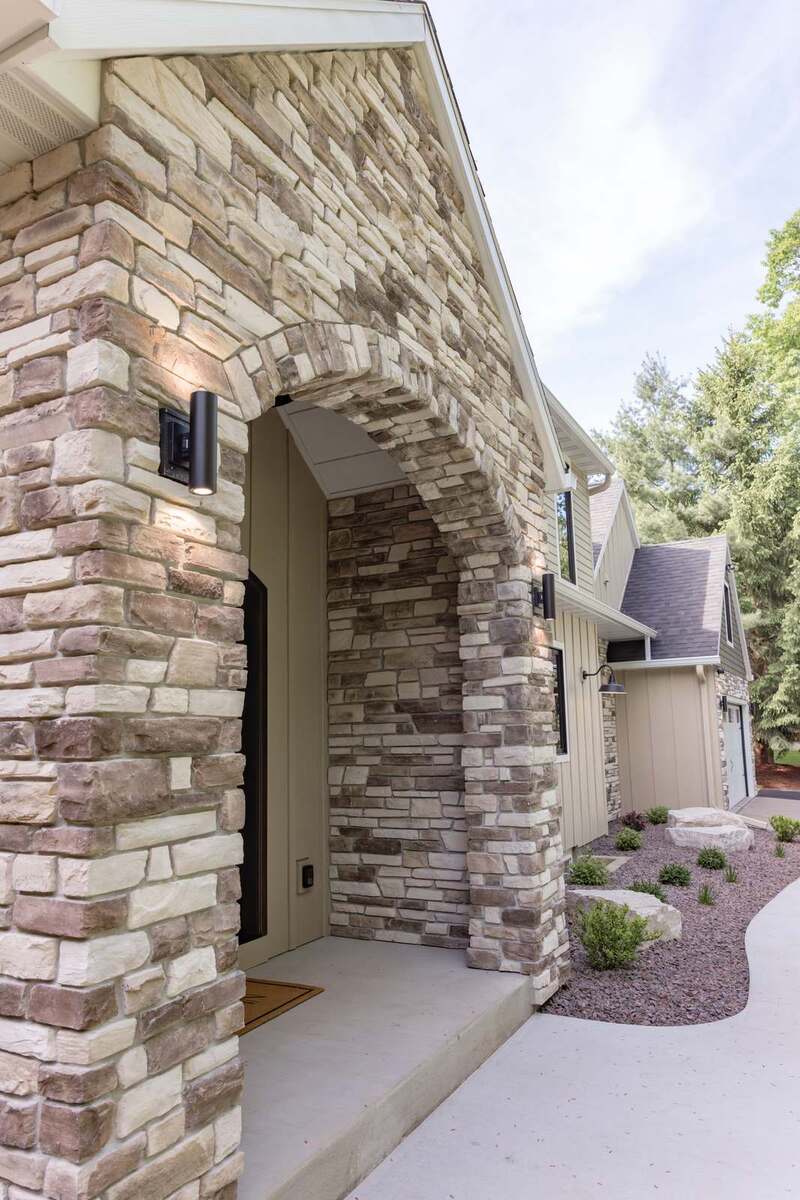 whole home remodel exterior stone arched porch with cylinder sconces minocqua wi