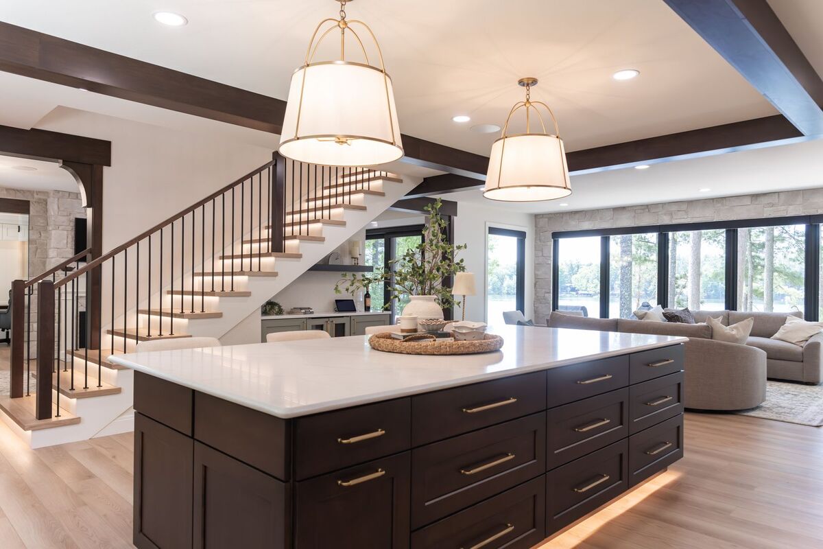 whole home remodel kitchen dark island with brass pendants and lighted staircase minocqua wi