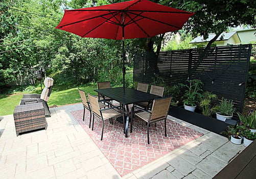 Outdoor dining area with red umbrella and modern patio layout by Ross Construction in Wausau, WI.