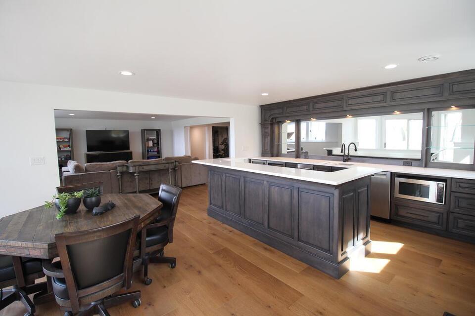 Custom basement wet bar with dark cabinetry and white quartz countertop by Ross Construction in Wausau, WI.