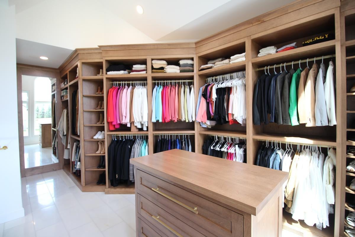Custom-built wardrobe wall with organized clothing and central dresser by Ross Construction in Wausau, WI