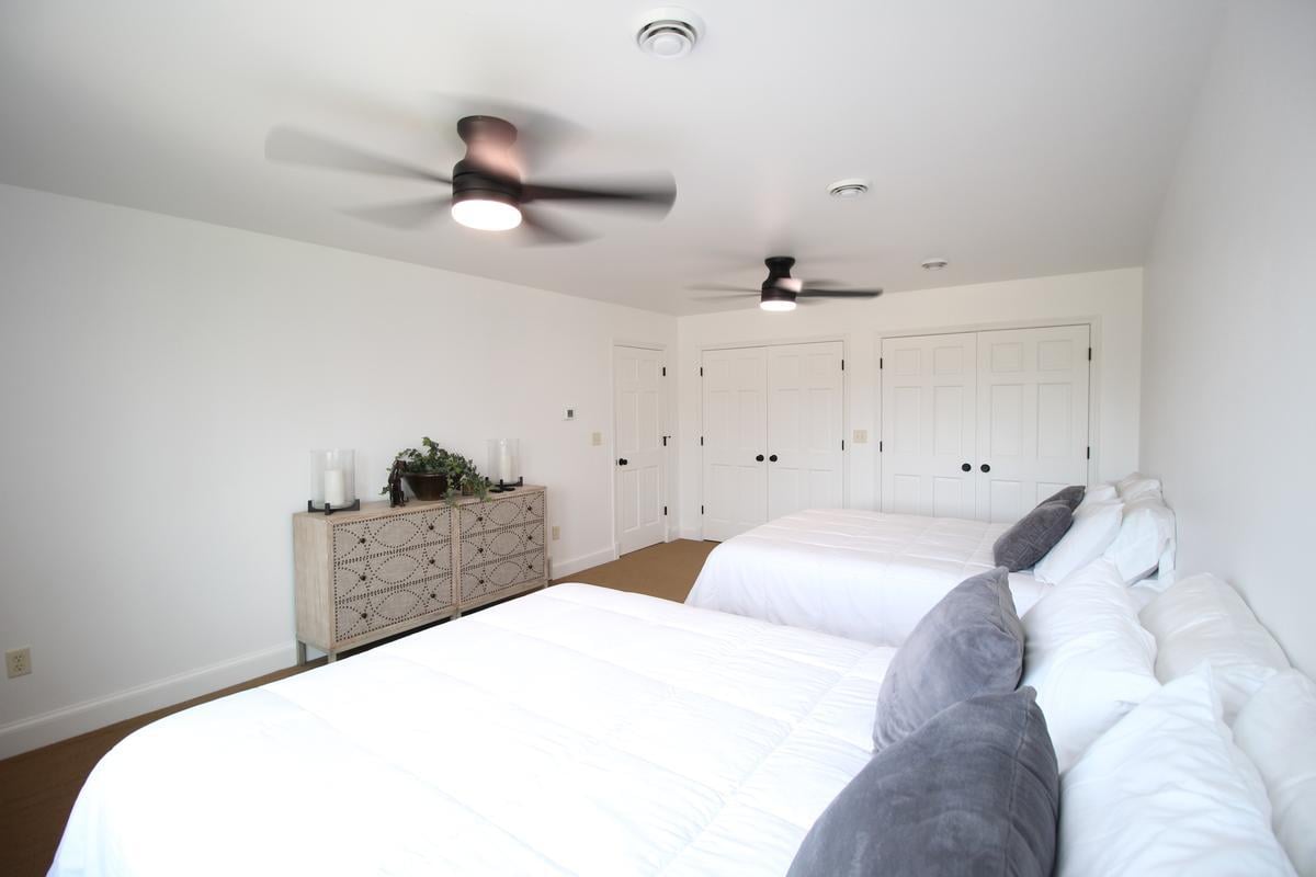 Guest bedroom with twin beds and ceiling fans by Ross Construction in Lake Dubay, WI