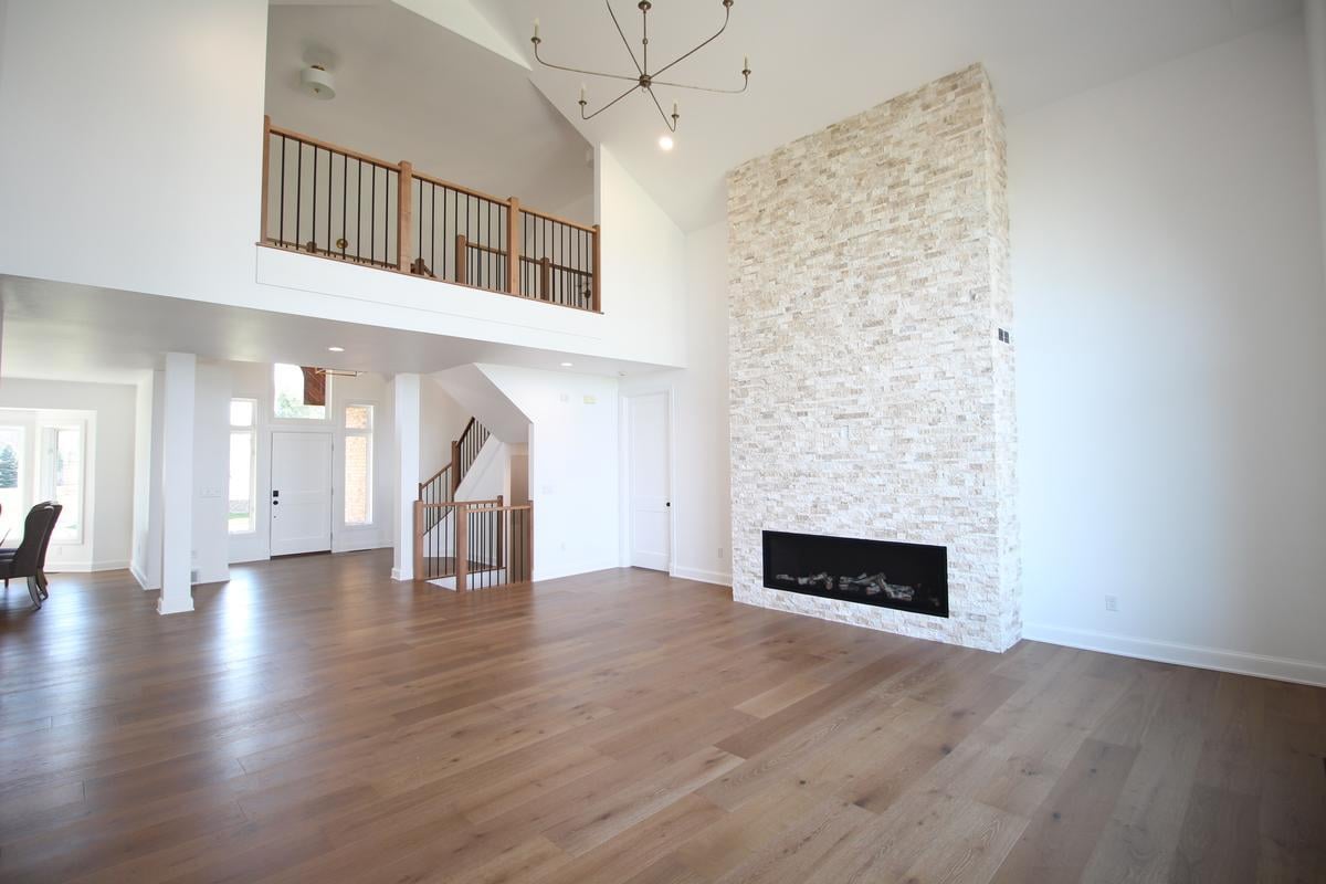 Open-concept living room with stone fireplace and vaulted ceiling by Ross Construction in Lake Dubay, WI