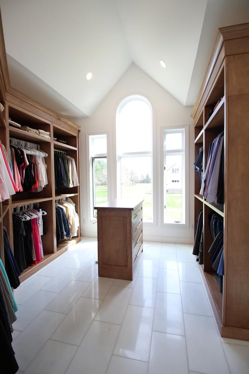 Walk-in closet with natural light and custom wood cabinetry by Ross Construction in Lake Dubay, WI