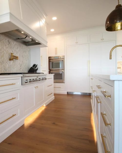 White luxury kitchen with brass pendant lights and large island by Ross Construction in Wausau, WI