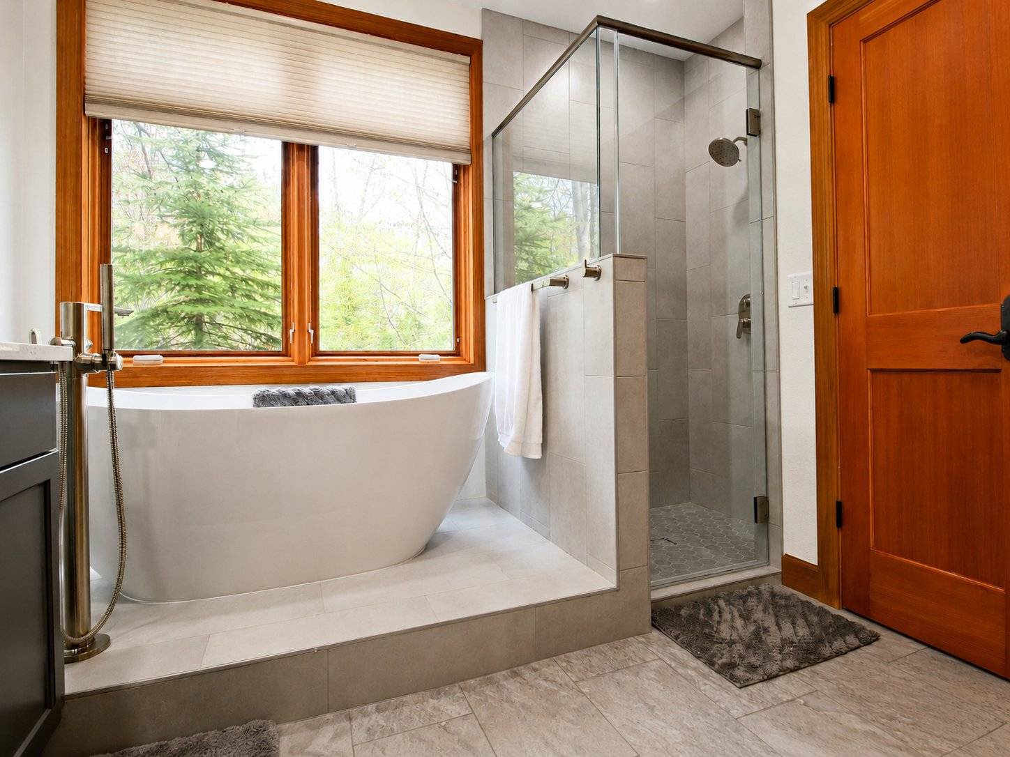 bathroom remodel freestanding tub glass shower wood window gray tile floor
