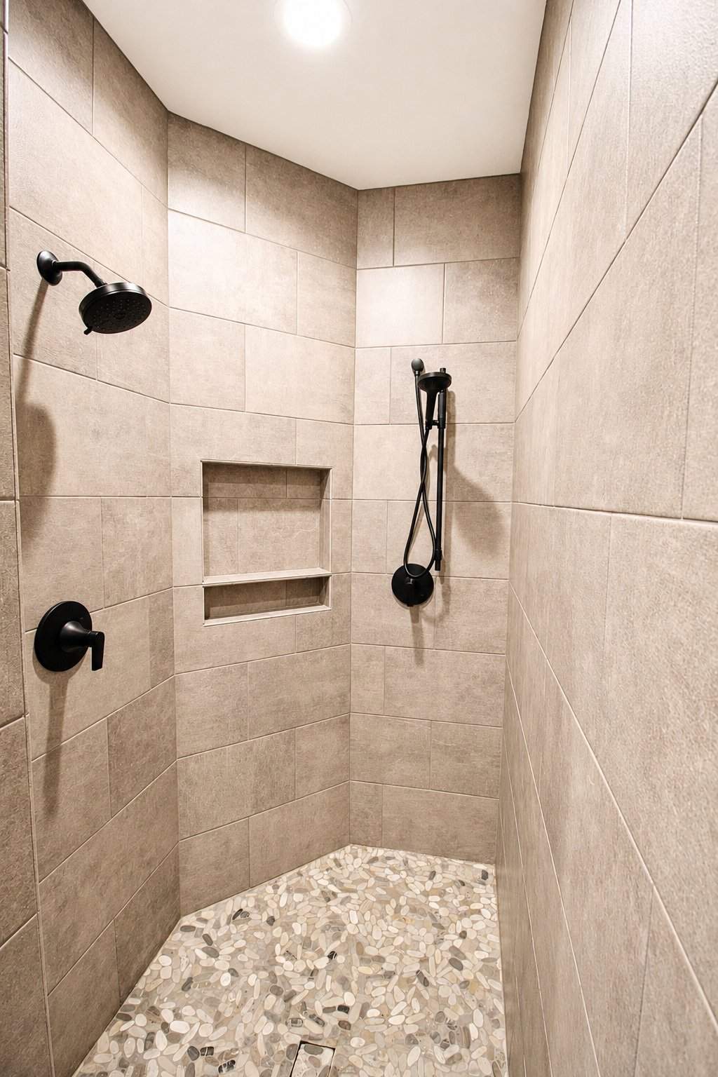 bathroom remodel walk in shower taupe tile black showerhead pebble floor niche