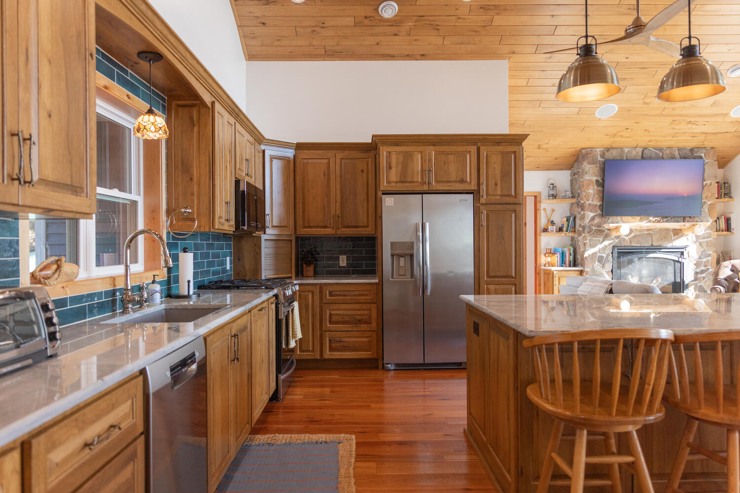 Rustic custom kitchen with wood cabinetry and green tile backsplash by Ross Construction in Marathon, WI.