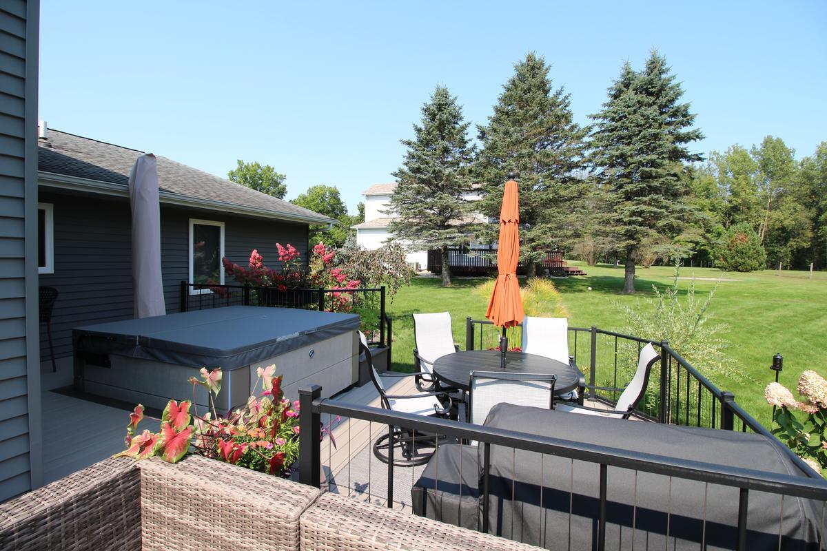 Round patio dining set with umbrella and hot tub on Ross Construction deck in Rib Mountain, WI