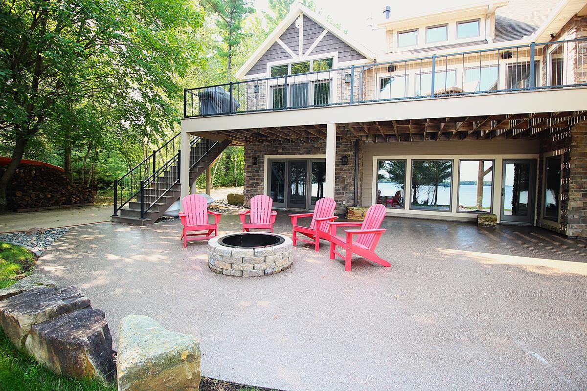 Walkout basement patio with red Adirondack chairs and fire pit by Ross Construction in Lake Dubay, WI