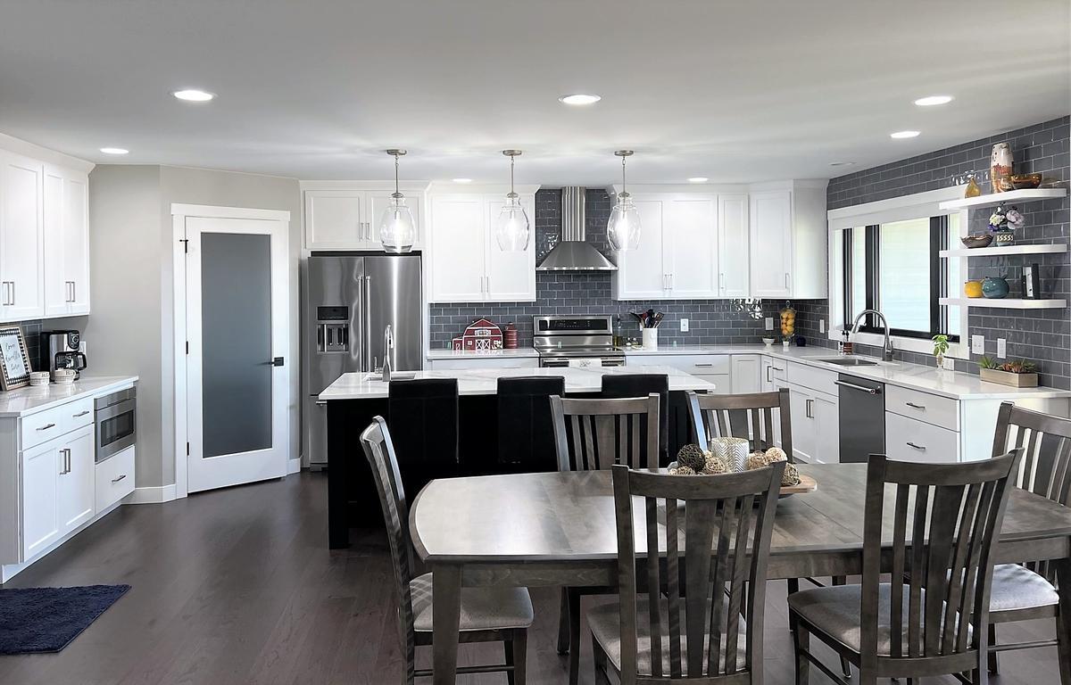 Modern kitchen with white cabinets and gray tile backsplash by Ross Construction in Lake Dubay, WI.