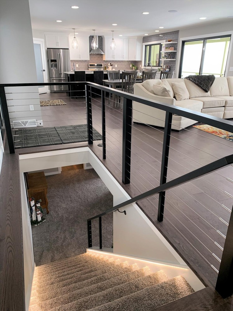 Open staircase leading into a modern kitchen and living area by Ross Construction in Lake Dubay, WI.
