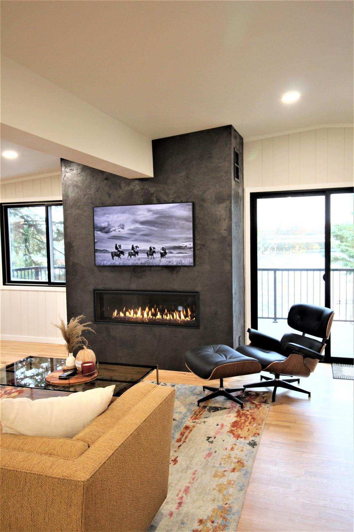 Sleek gas fireplace with lounge chair in custom living room by Ross Construction in Lake Dubay, WI.