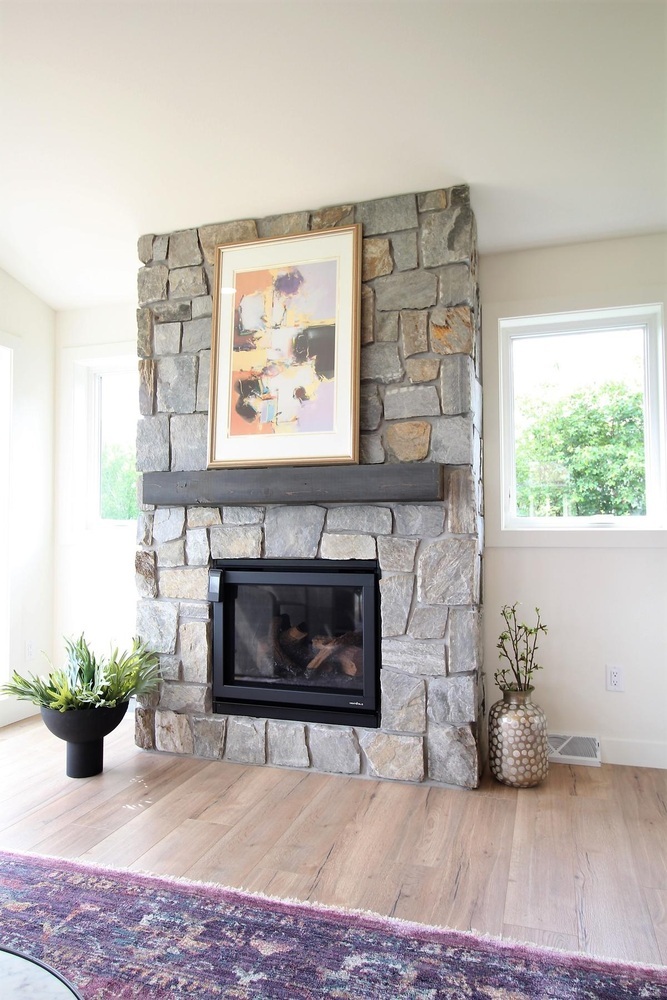 Stone fireplace with artwork and modern decor in custom living room by Ross Construction in Rib Mountain, WI